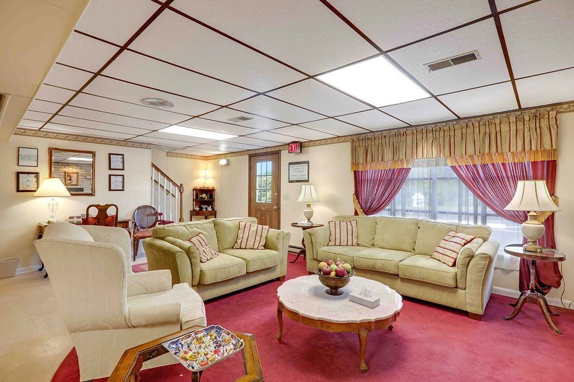Bright living room with cream sofas, red carpet, coffee table, and large curtained windows
