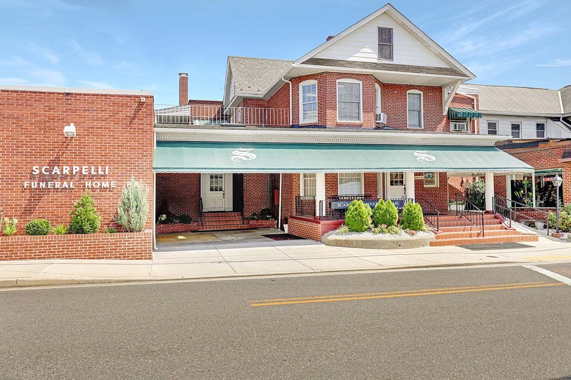 Historic brick storefront with green awning and white sign beside a roadside curb
