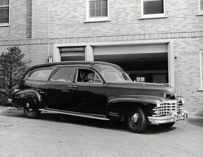 Black vintage station wagon parked in front of a brick garage