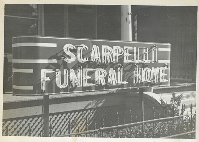 Black-and-white sign reading “Scarpelli Funeral Home” on a building facade