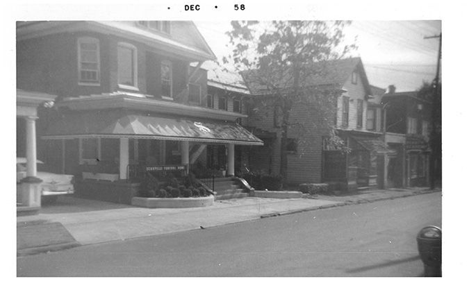 Quiet residential street with brick houses and a porch awning on the left.