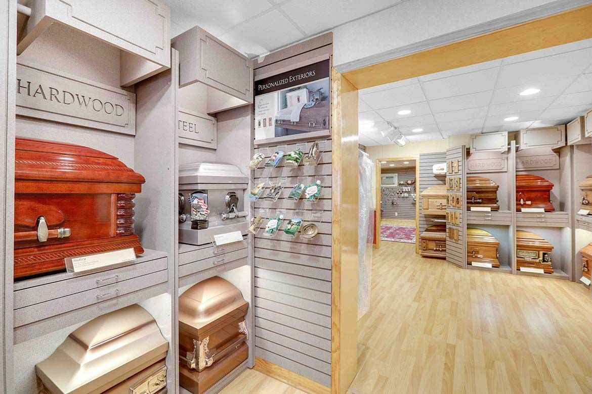 Funeral showroom with several wooden and metal coffins displayed in a bright showroom