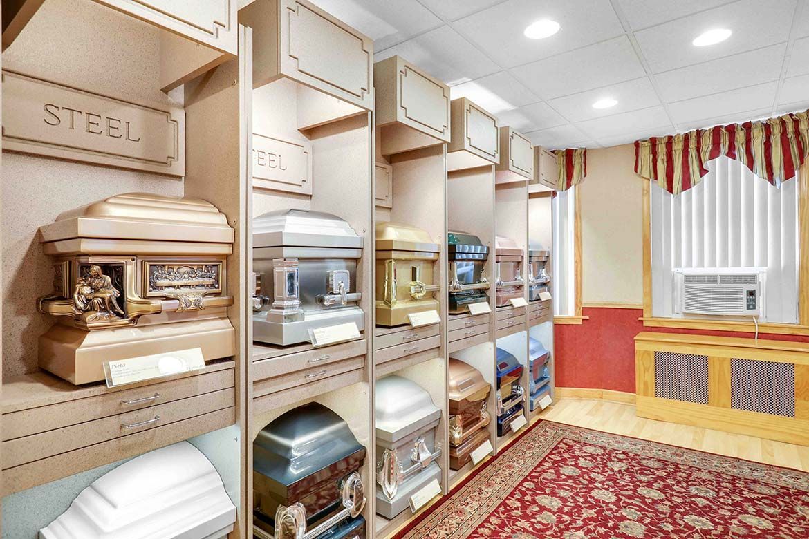 Display room with caskets on shelves, red carpet, and a white draped table in a bright showroom