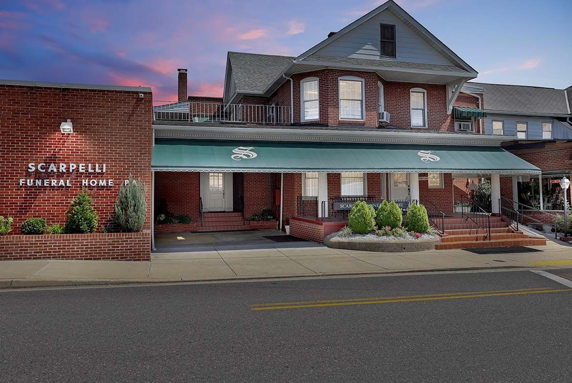 Historic brick storefront with green awning and sign reading “SCARPELLI” at dusk.
