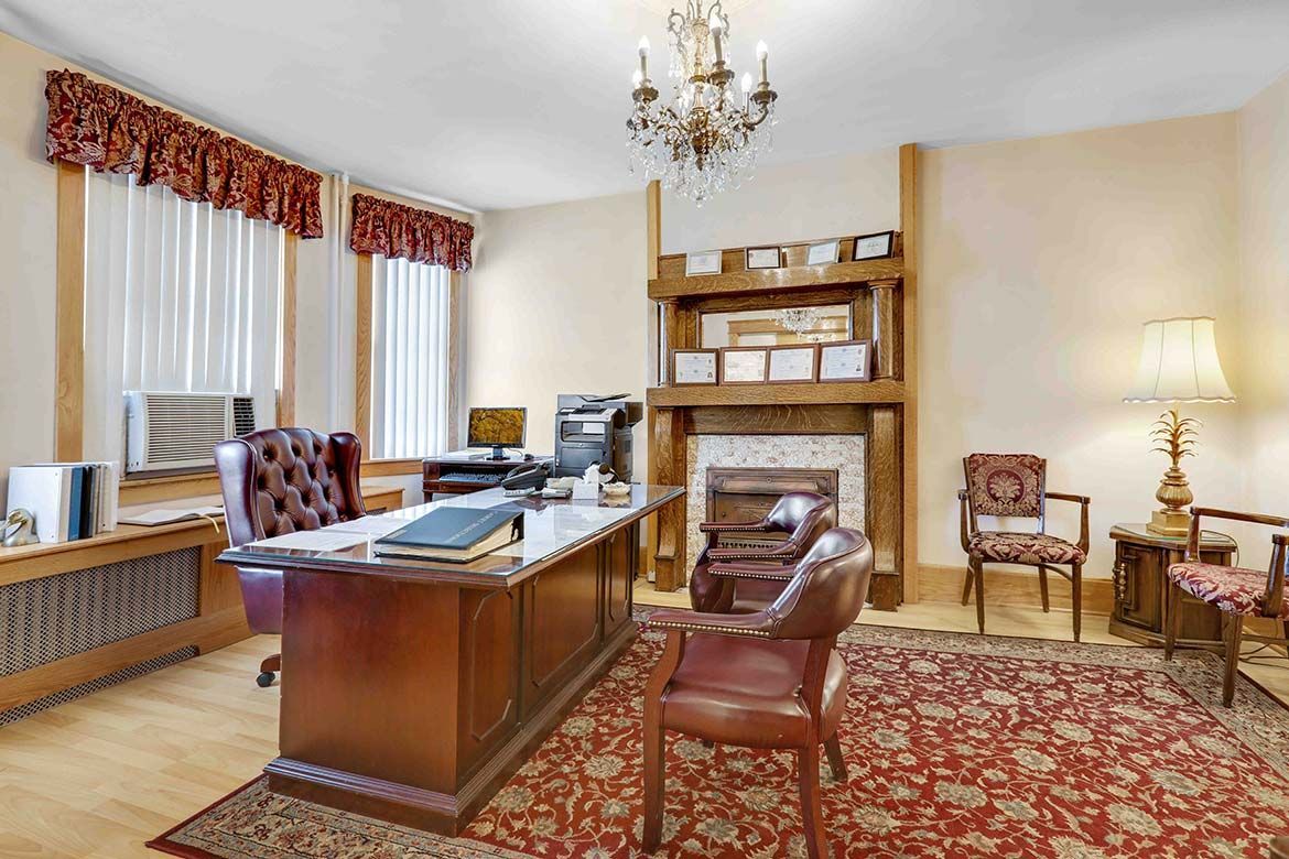 Elegant office with a wooden desk, bookshelf, fireplace, and red patterned rug