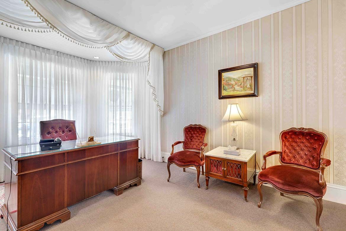 Elegant living room with sheer drapes, wood console, red chairs, and a lit table lamp