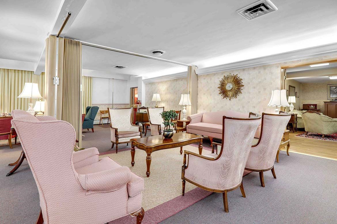 Elegant lounge with pink armchairs, wooden tables, lamps, and mirrored walls in a bright room