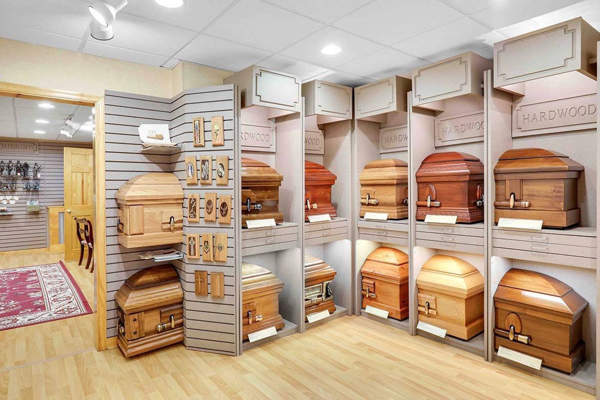 Display of wooden coffins in a bright showroom with shelves and polished wood flooring