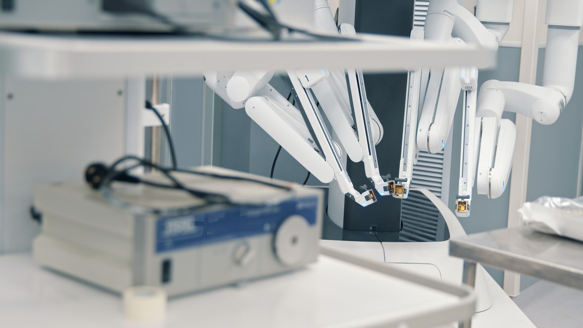 A surgical robot is sitting on a table in a hospital room.