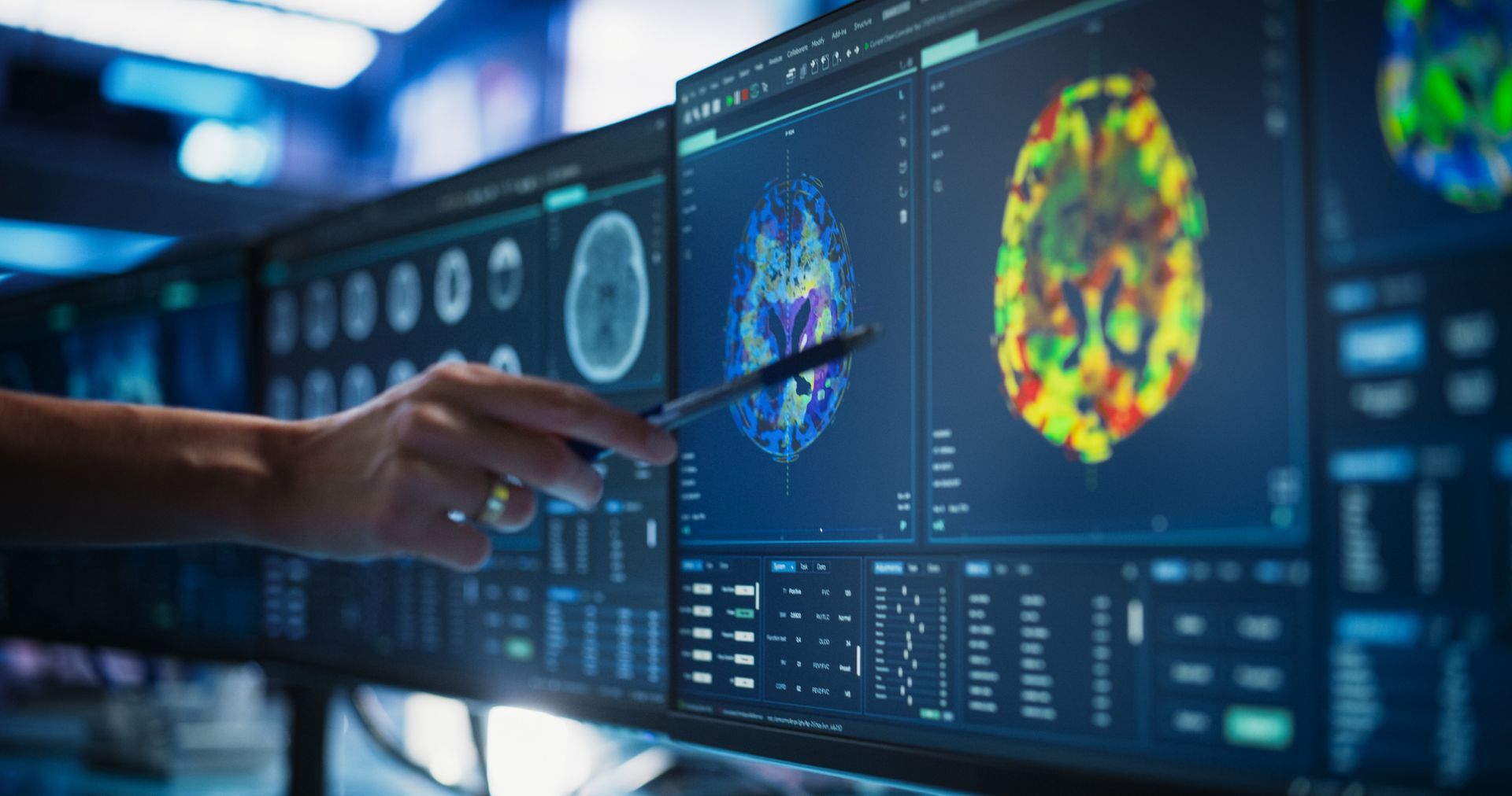 A person is pointing at a computer screen with a picture of a brain on it.