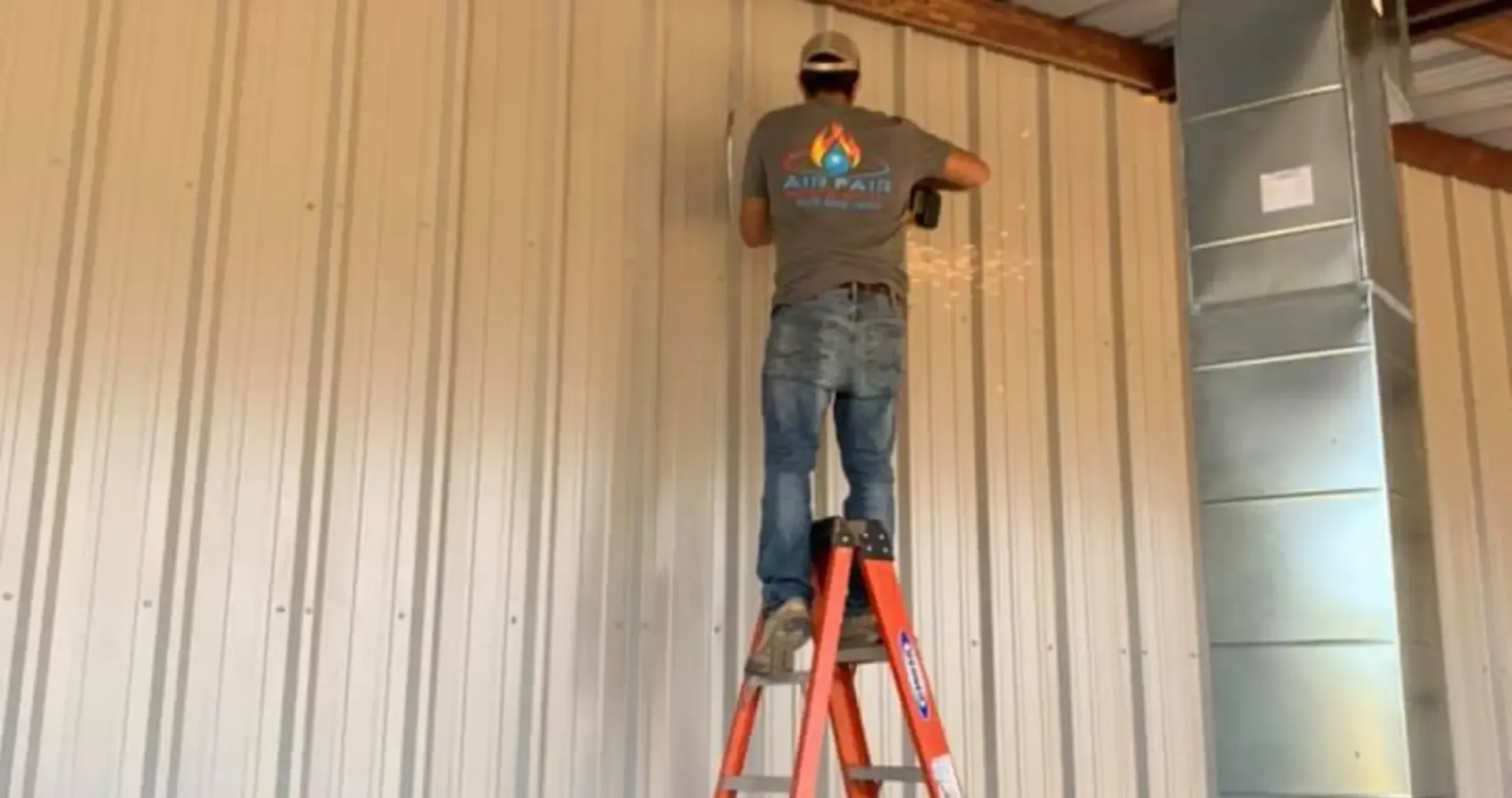 Air Fair Heat and Air LLC - A man is standing on a ladder working on a wall.