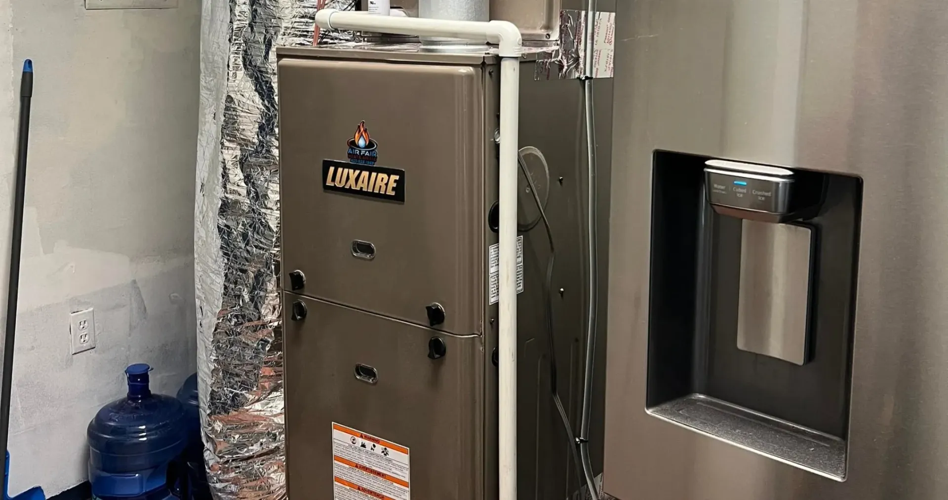 Air Fair Heat and Air LLC - A furnace is sitting in a room next to a refrigerator.