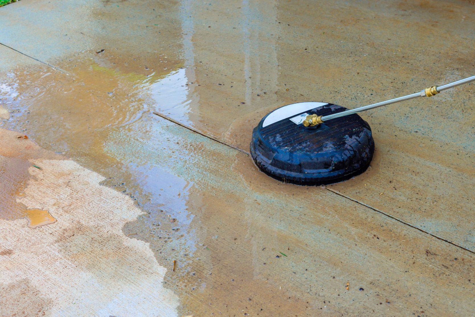 Pressure washer cleaning a wet, stained patio.