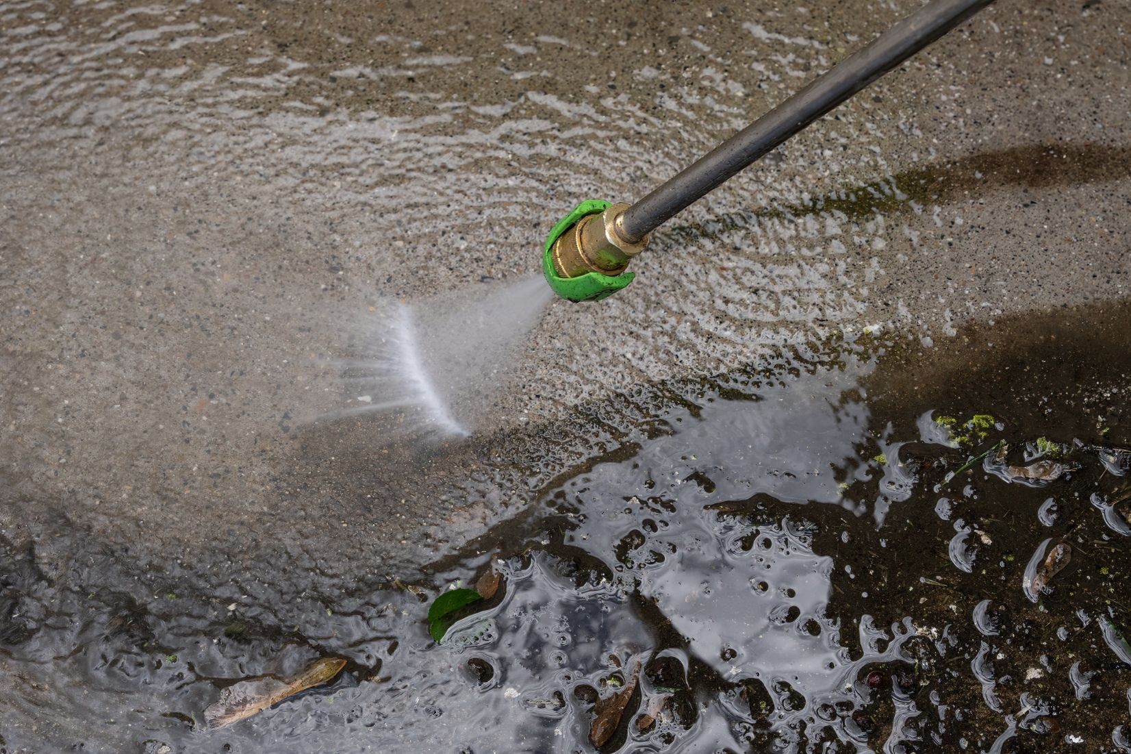 Pressure washer spraying water on concrete surface.