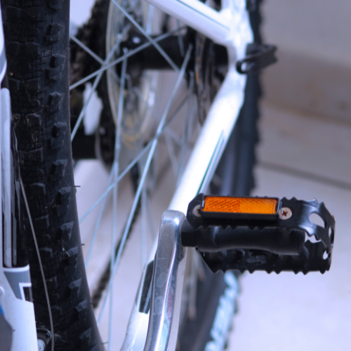Een close-up van een fietspedaal met een oranje reflector