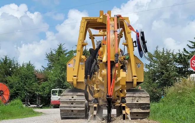 A yellow bulldozer is driving down a dirt road next to a stop sign
