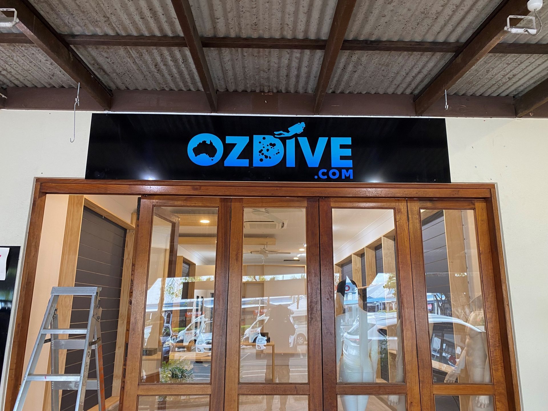 Storefront With Wooden Doors and a Blue Sign Under a Metal Roof — On The Spot Signs Port Douglas In Port Douglas, QLD