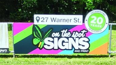 A colorful sign for On the Spot Signs and Print located at 27 Warner St., celebrating 20 years in business.