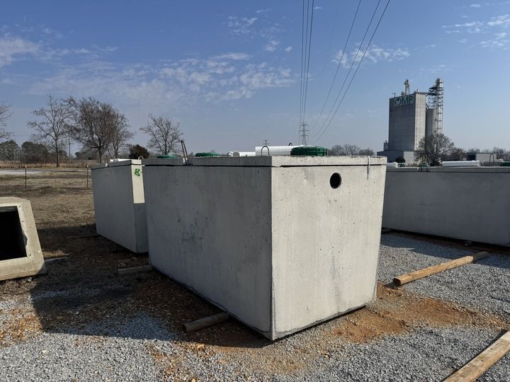 Concrete rectangular tanks outdoors on a gravel surface, possibly for wastewater treatment.