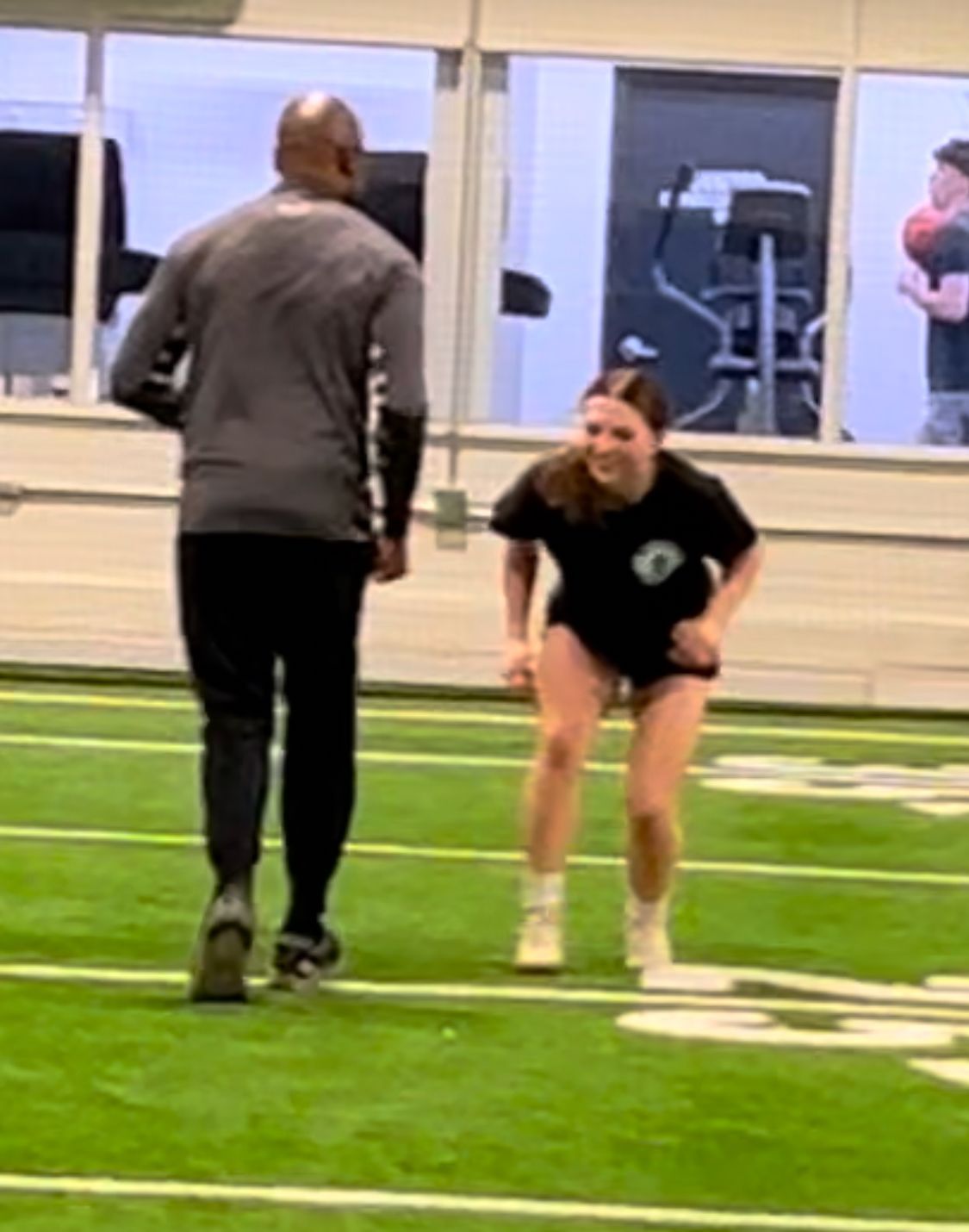 A man and a woman are standing on a football field.
