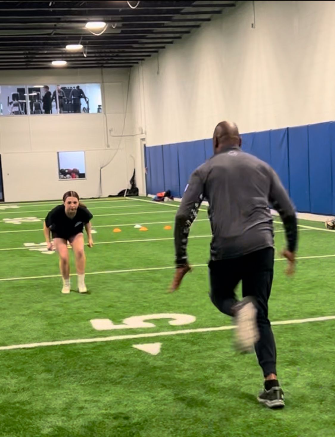 A man and a woman are running on a football field.