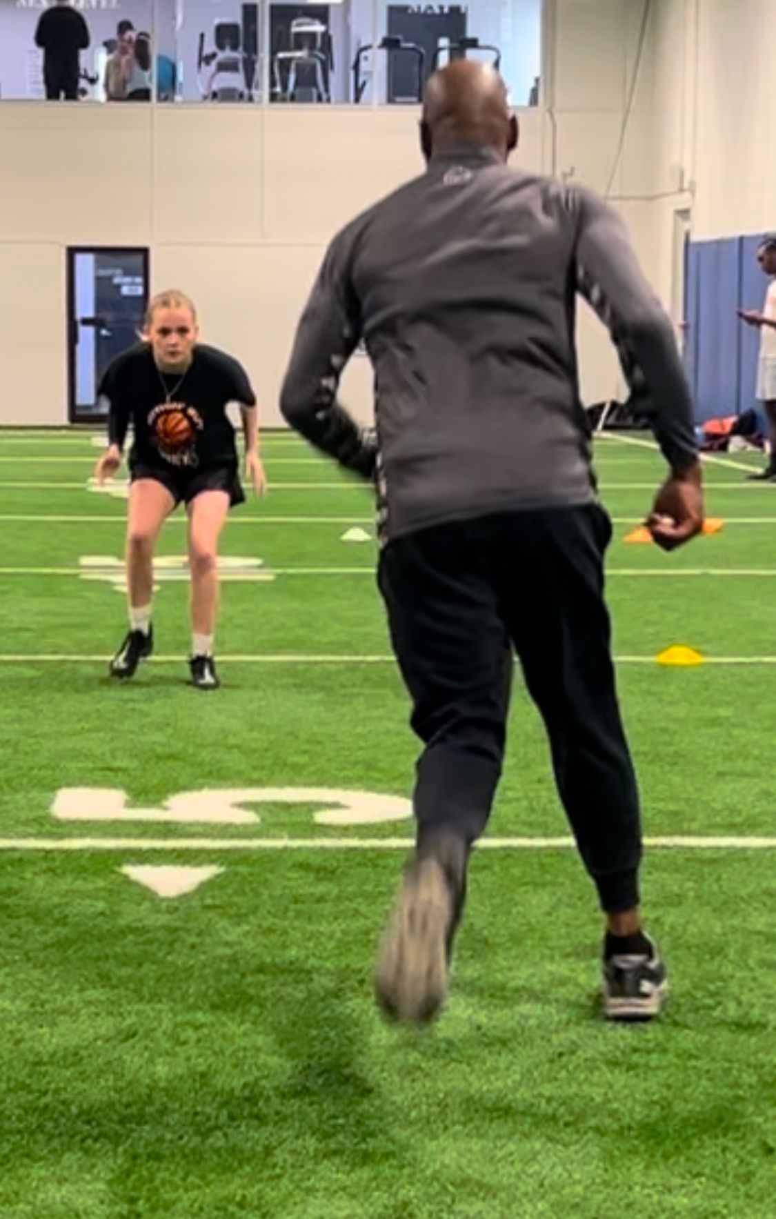 A man and a woman are running on a football field.