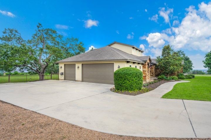 Garage of a beige house with two doors, driveway, and landscaping under a blue sky.