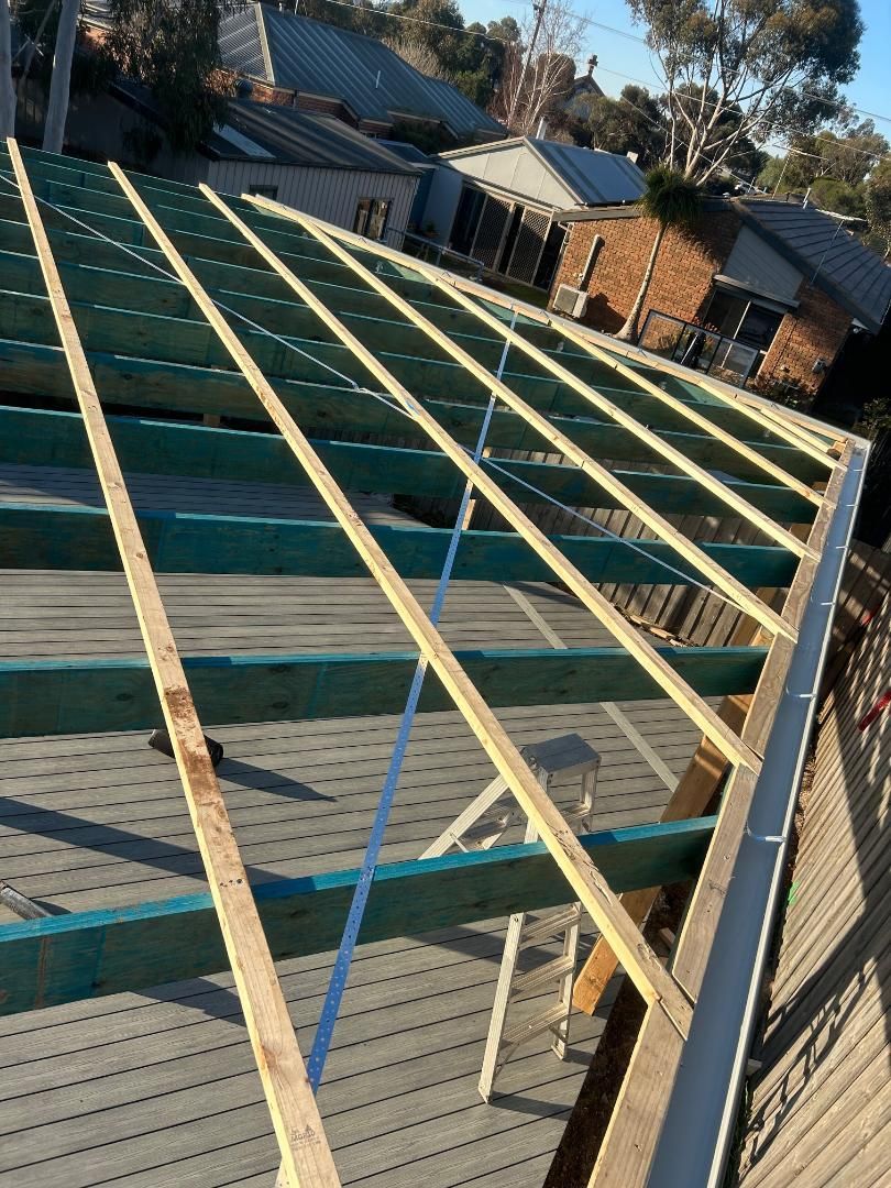 The roof of a house is being built with wooden beams before a full new roof replacement