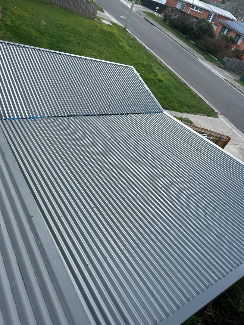 An aerial view of a previous rusty metal roof that has been fully repaired with a new mental roof replacement