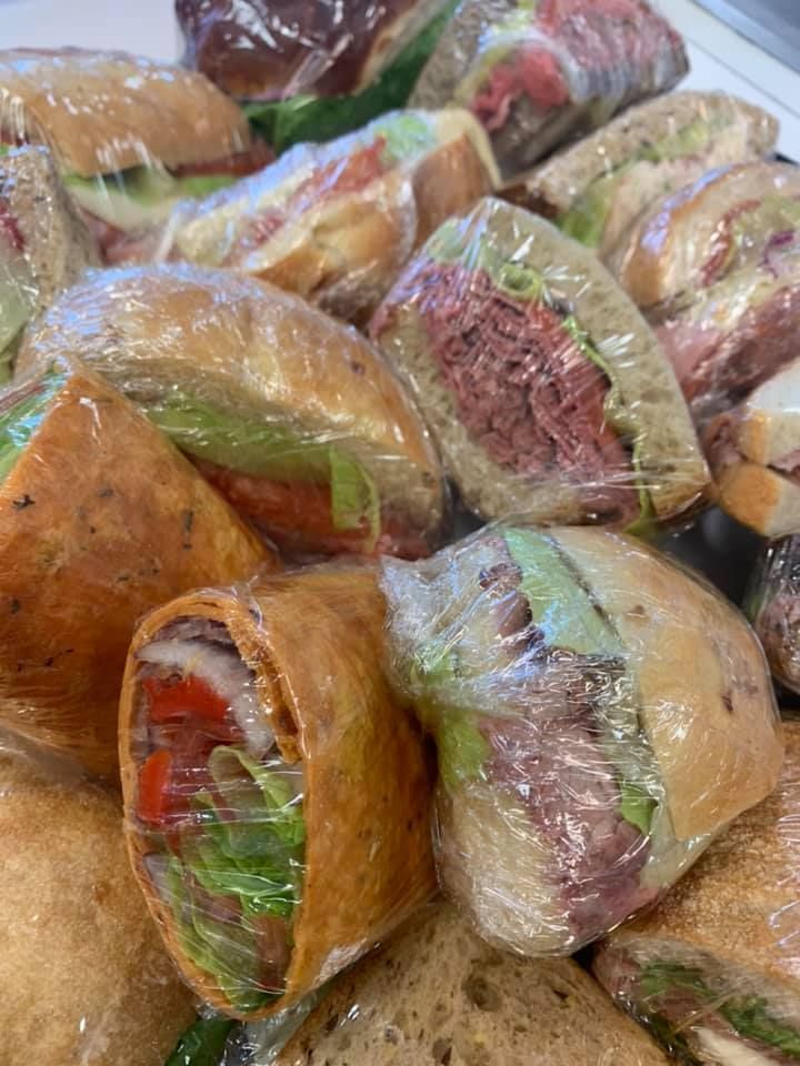 Plastic-wrapped tortillas stuffed with vegetables, stacked in a market display