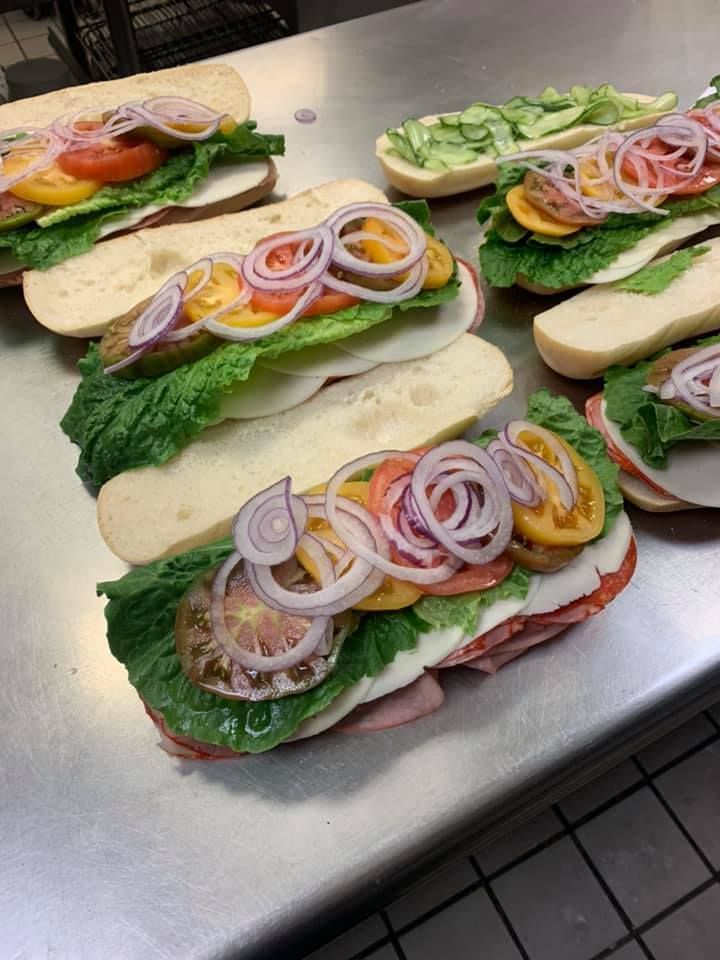 Open-faced sandwiches with lettuce, tomato, onion, and cucumber arranged on a metal tray