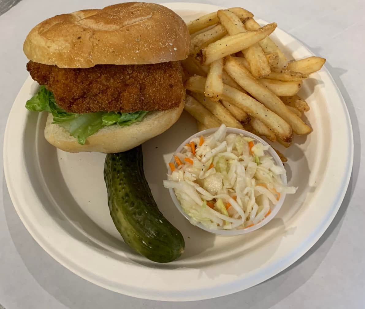 Sandwich, fries, pickle, and coleslaw on a white plate