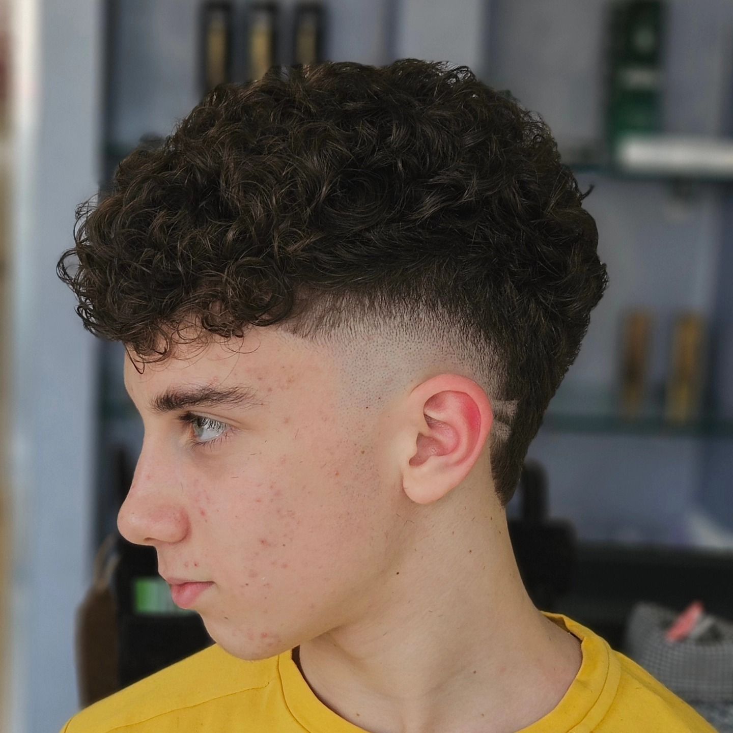 Un giovane con i capelli ricci indossa una maglietta gialla