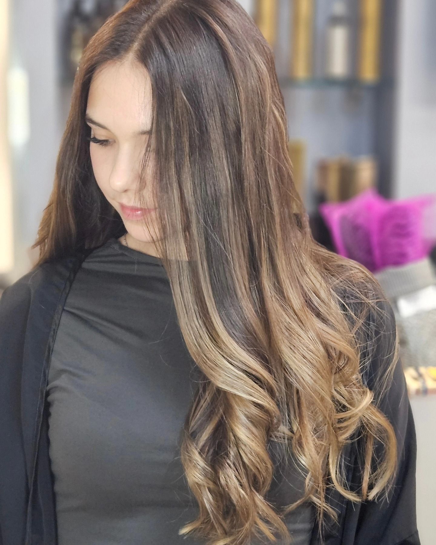 Una donna con i capelli lunghi indossa una camicia nera e un cardigan nero.