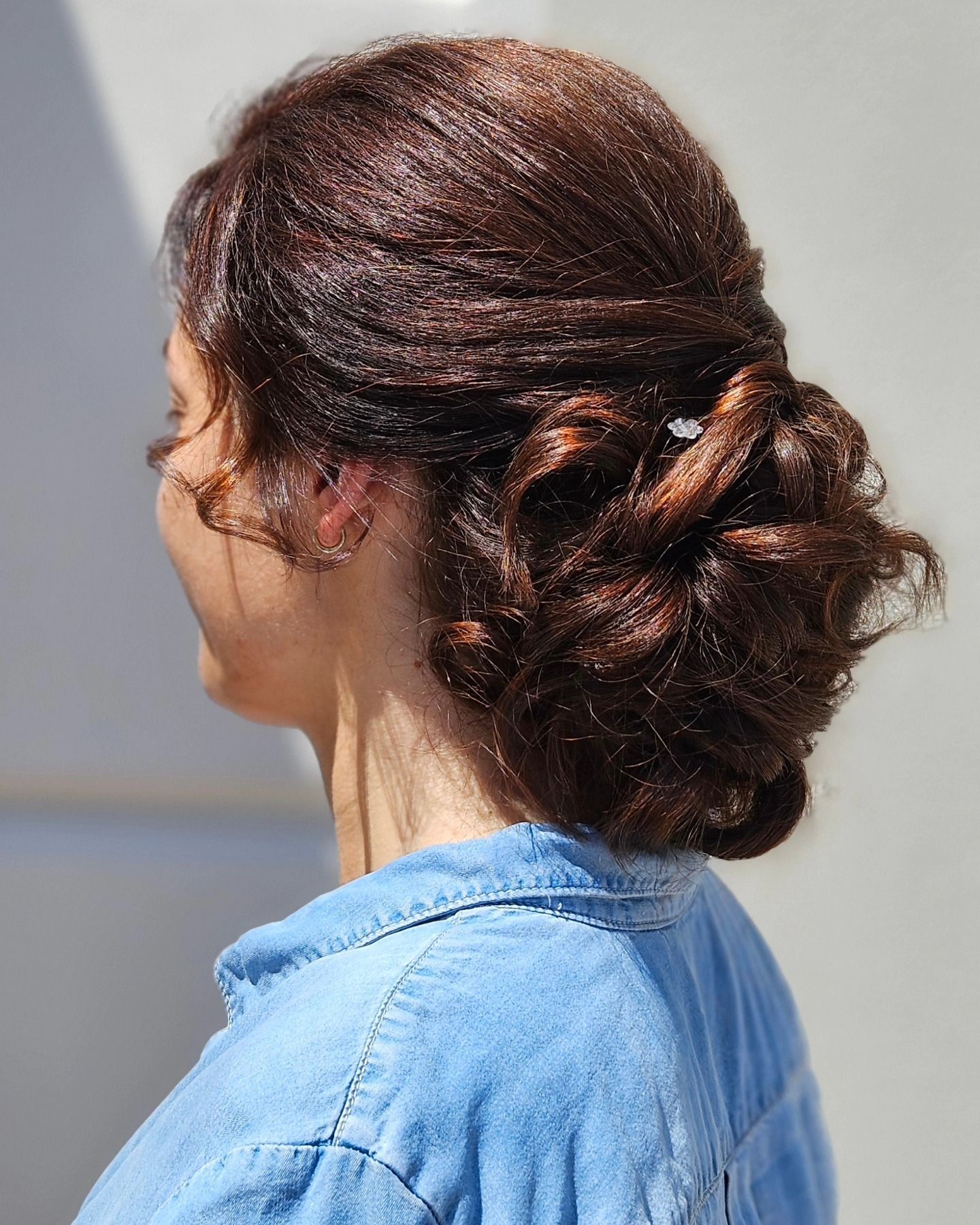 La donna indossa una maglietta blu e ha i capelli raccolti in uno chignon.