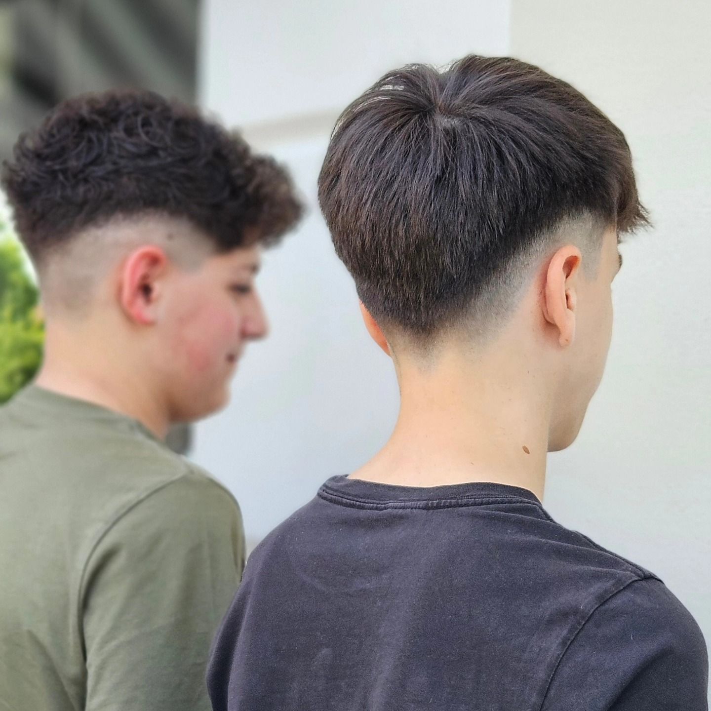 Due giovani sono in piedi uno accanto all'altro e uno ha un taglio di capelli molto corto.