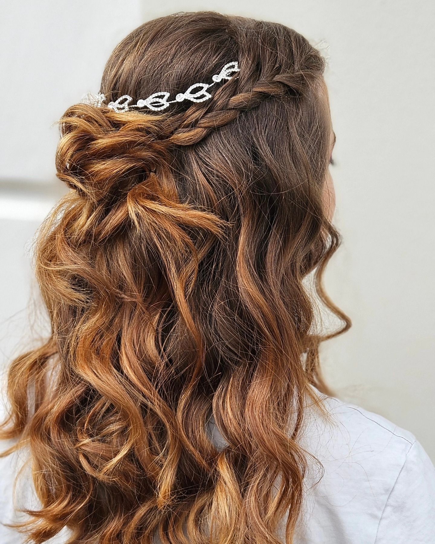 Una donna con lunghi capelli castani porta un'acconciatura metà raccolta e metà sciolta con una treccia.