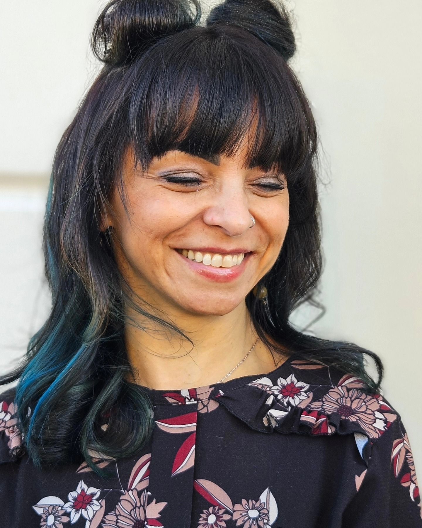 Una donna con i capelli blu sorride e indossa una camicia floreale