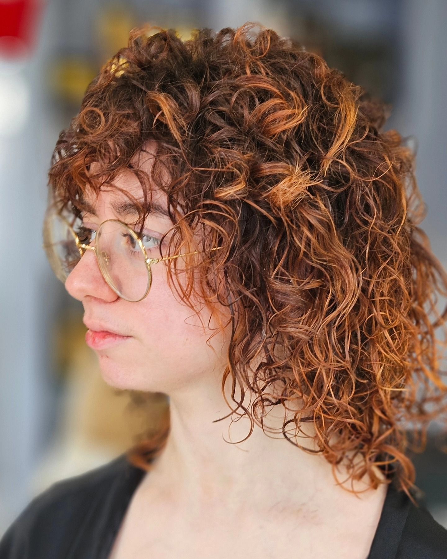 Una donna con i capelli ricci e gli occhiali indossa una camicia nera.