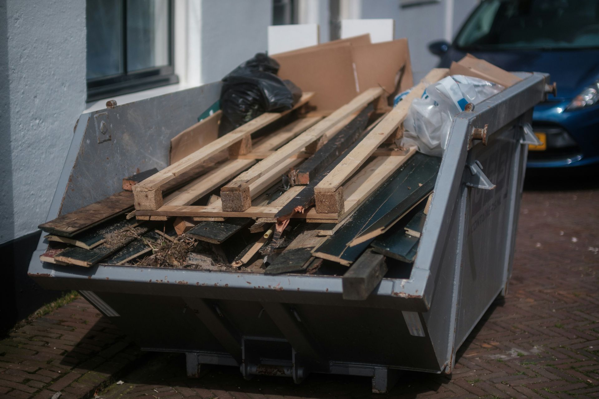 Pallets, flooring, and other construction materials loaded up into a garbage container.