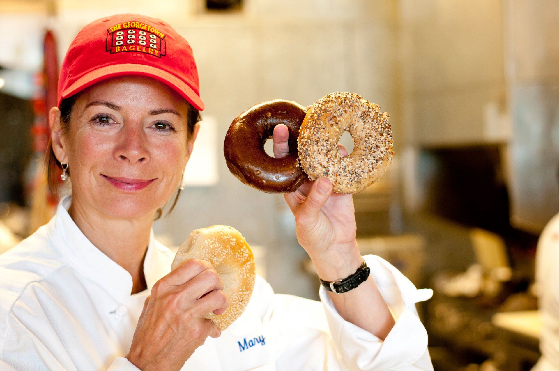 Woman holding three bagels — Bethesda, MD — Georgetown Bagelry Woman holding three bagels — Bethesda, MD — Georgetown Bagelry