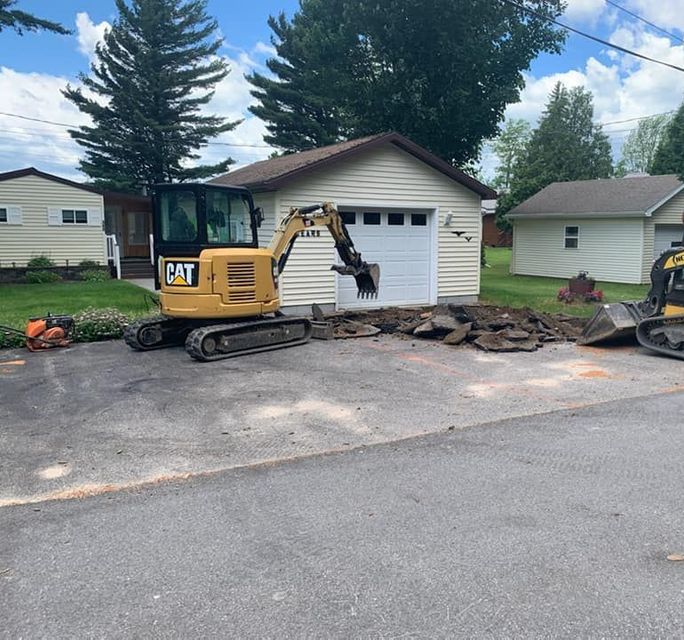 A cat excavator is parked in front of a house