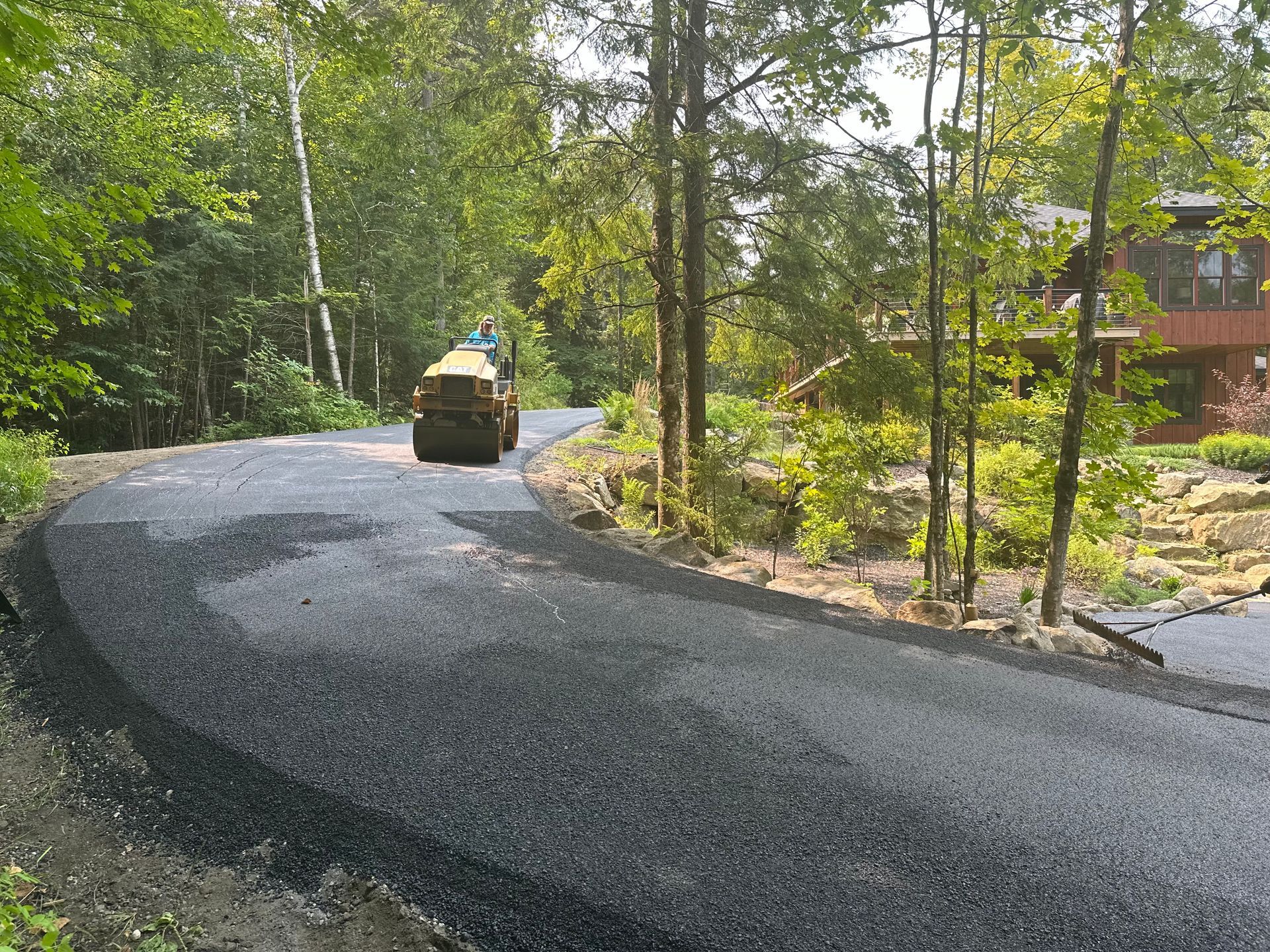 A roller is rolling asphalt on a curvy road.
