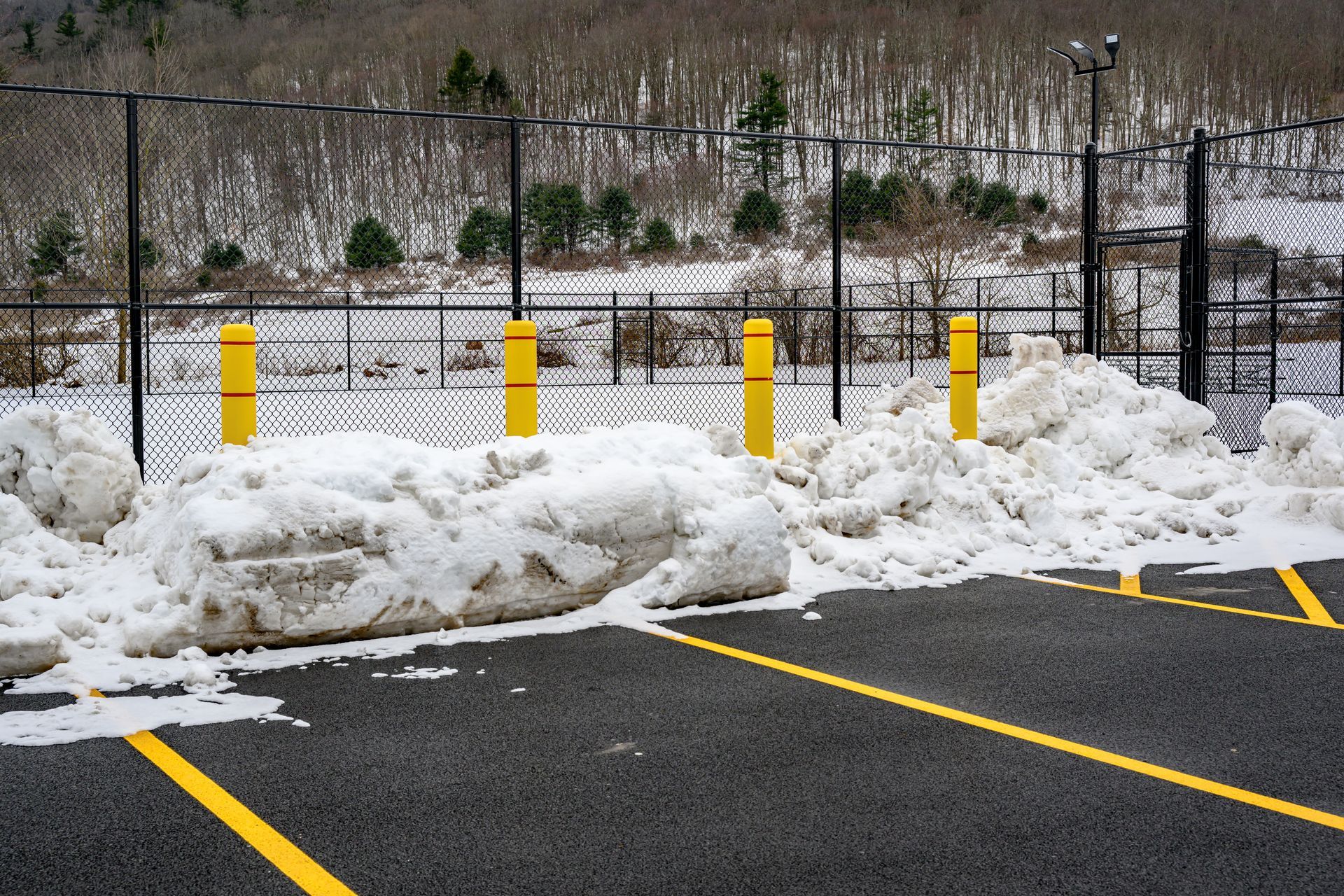 A parking lot with snow on the ground and yellow poles