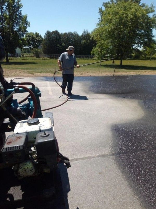 A man is spraying a driveway with a hose