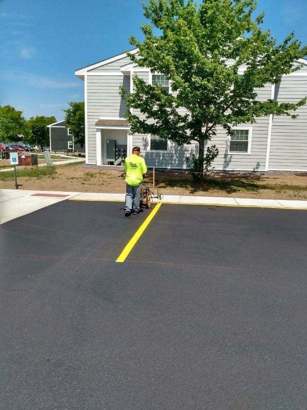 A man is painting a yellow line in a parking lot