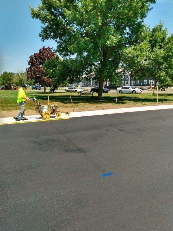 A man is using a machine to paint a blue line on the road