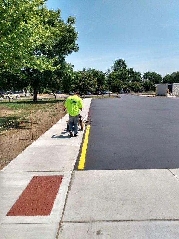 A man is walking down a sidewalk next to a parking lot.