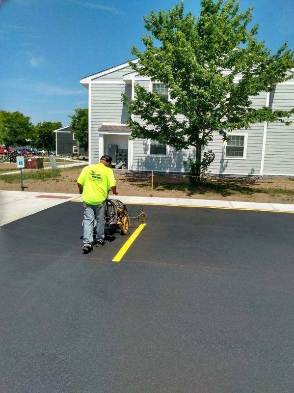 A man is painting a yellow line in a parking lot