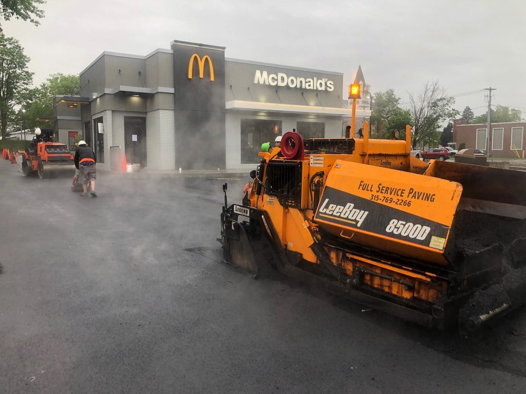A mcdonald 's is being paved in front of a construction vehicle.